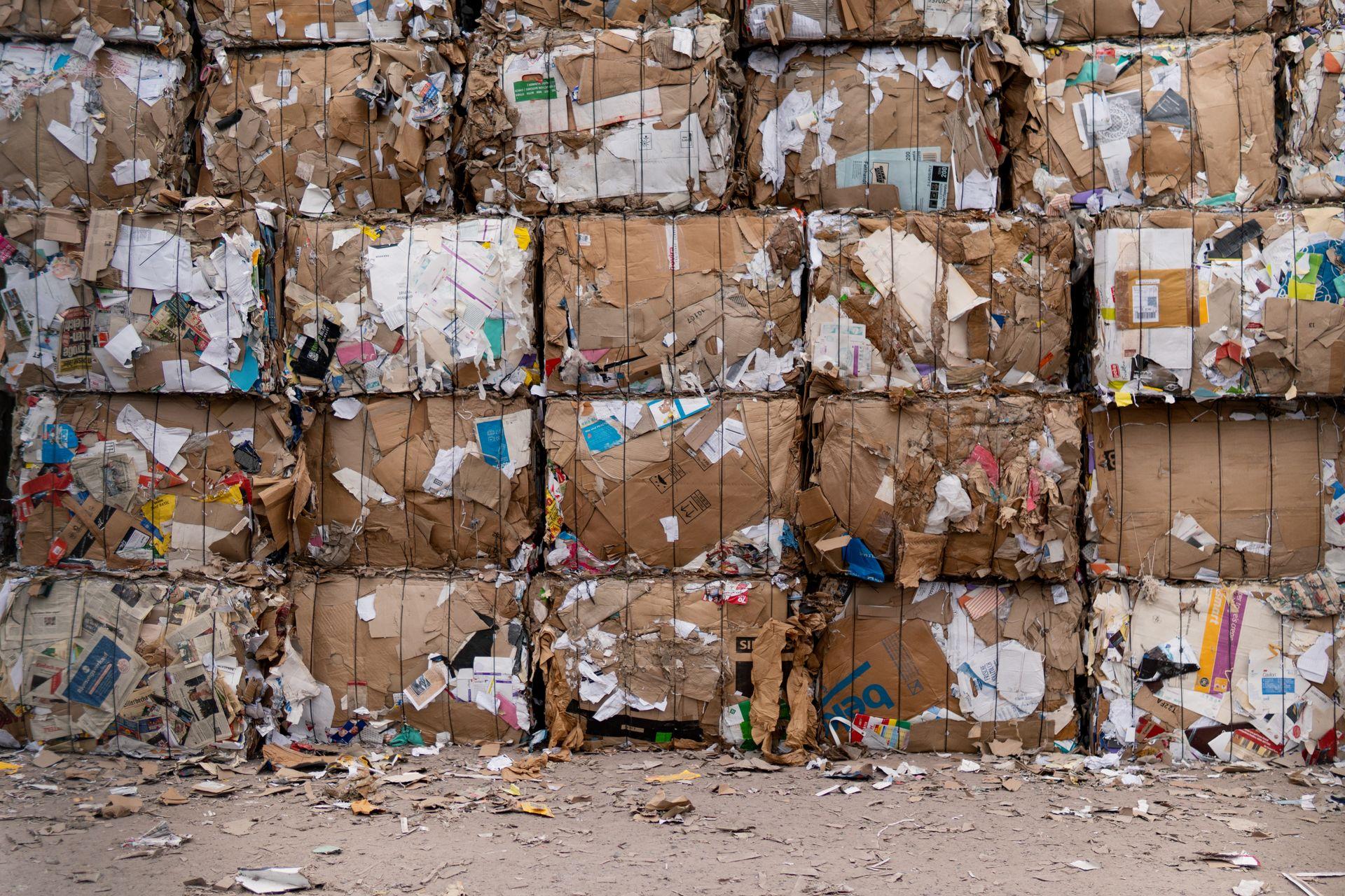 Large bales of recovered cardboard stacked outdoors, ready for processing